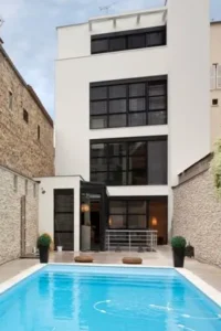 Maison de ville contemporaine en cœur d’îlot, façade blanche, grandes baies vitrées et piscine en cour intérieure, conçue par Le Quilleuc Architecte.